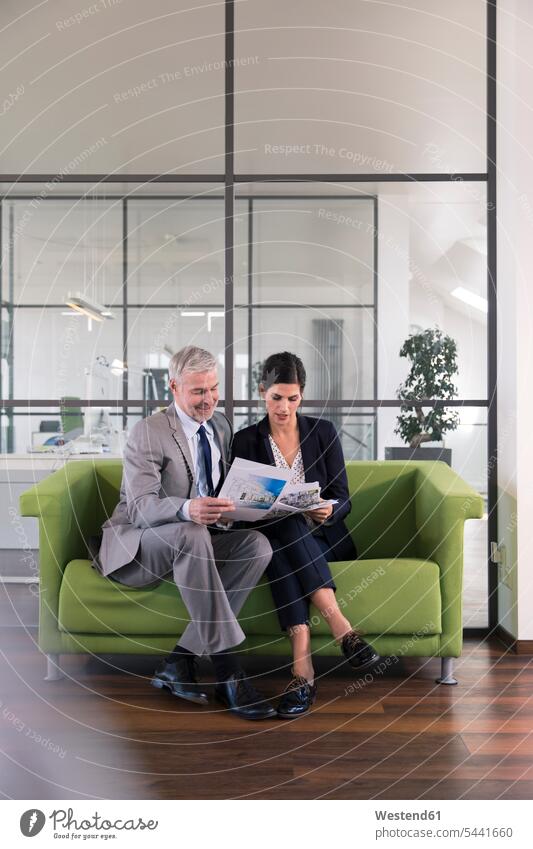 Businessman and woman sitting on couch in office looking at documents customer consulting Planning planning planned Conception Conceptions planning office