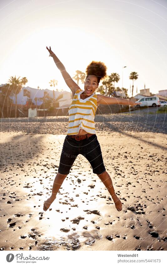 Happy woman jumping in the air on the beach females women jump in the air beaches Adults grown-ups grownups adult people persons human being humans human beings