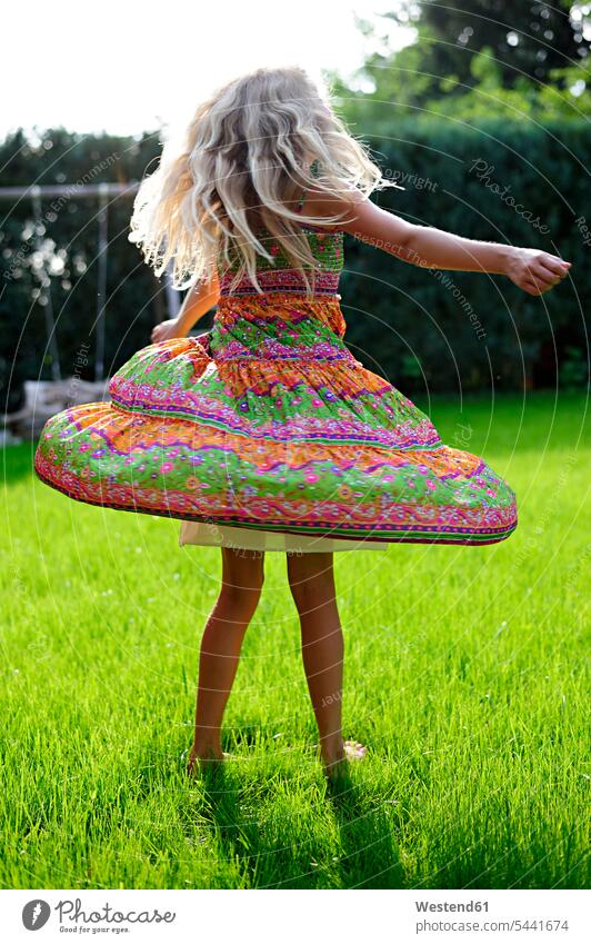 Girl wearing a dress turning in garden girl females girls dresses gardens domestic garden child children kid kids people persons human being humans human beings