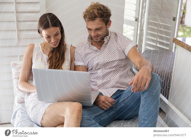 Smiling young couple sharing laptop twosomes partnership couples smiling smile Laptop Computers laptops notebook people persons human being humans human beings