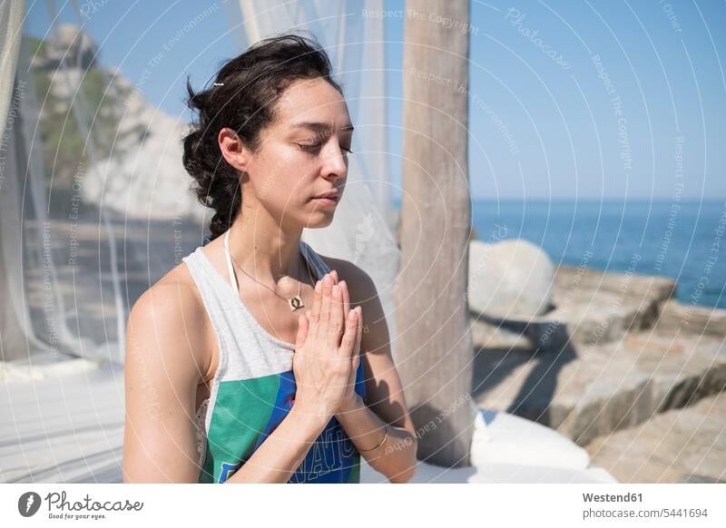 Woman doing a yoga exercise at the coast meditating meditate Yoga woman females women practicing practice practise exercising practising coastline shoreline