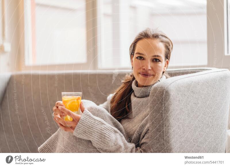 Portrait of woman sitting on couch holding fresh drink Seated smiling smile females women Adults grown-ups grownups adult people persons human being humans