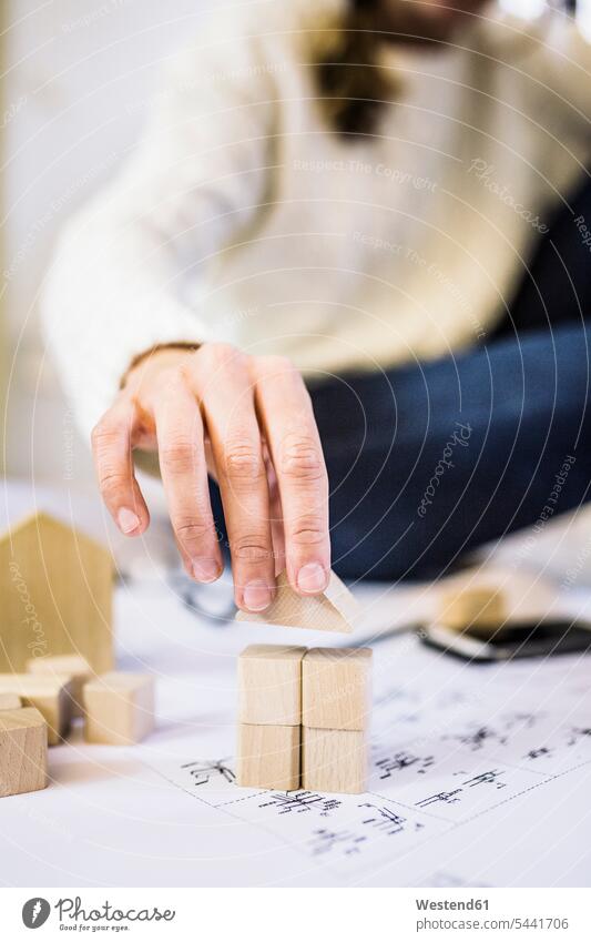 Woman placing building brick house on blueprint place Block Toy Block Toys building bricks Toy Blocks houses woman females women Blueprint Blueprints