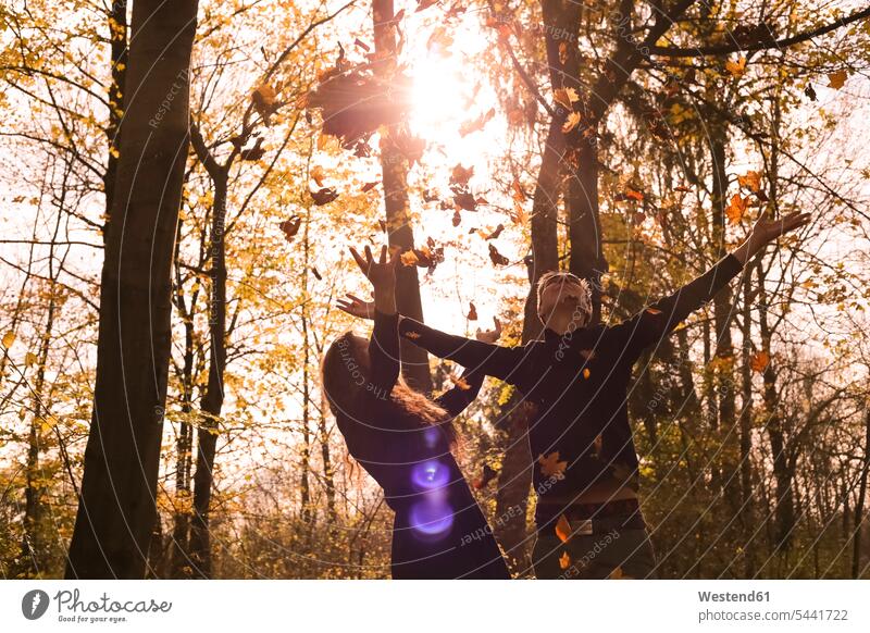 Happy couple in the forest in autumn throwing leaves in the air happiness happy woods forests Leaf Leaves twosomes partnership couples fall people persons