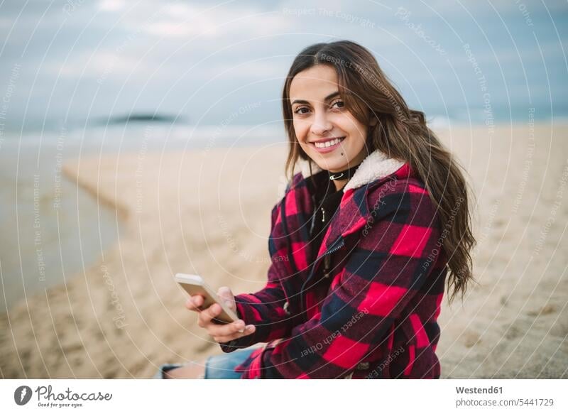 Portrait of smiling young woman with smartphone on the beach beaches females women portrait portraits Adults grown-ups grownups adult people persons human being