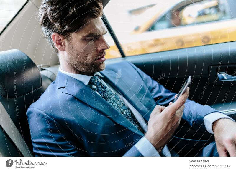 Businessman sitting in taxi, using smart phone attractive beautiful pretty good-looking Attractiveness Handsome yellow cab reading Seated Business man
