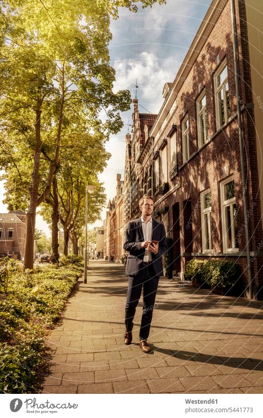 Netherlands, Venlo, businessman with cell phone walking on pavement Side Walk going city town cities towns Businessman Business man Businessmen Business men