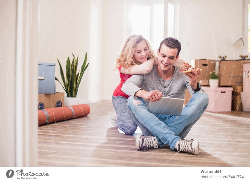 Young couple in new home sitting on floor with tablet flat flats apartment apartments twosomes partnership couples people persons human being humans