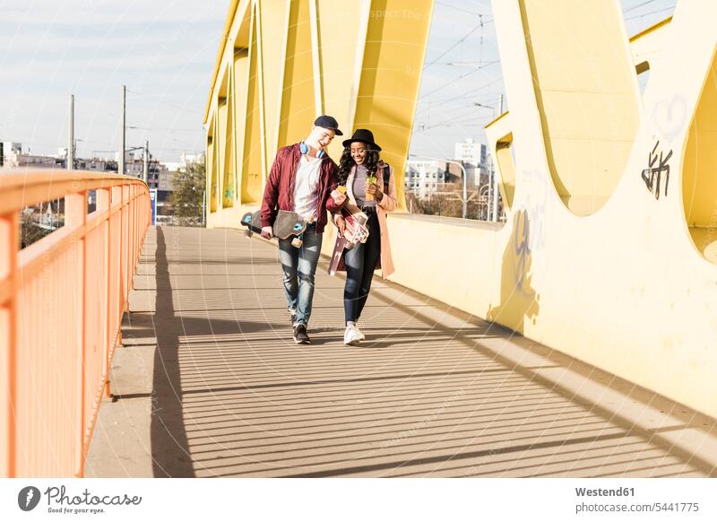 Young couple with skateboard walking on bridge Fun having fun funny bridges young happiness happy cheerful gaiety Joyous glad Cheerfulness exhilaration merry