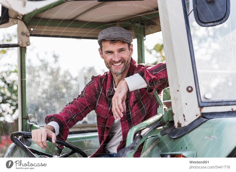 Portrait of confident farmer on tractor smiling smile portrait portraits agriculturists farmers man men males motor vehicle road vehicle road vehicles