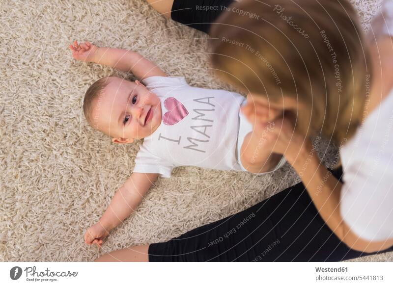 Mother and baby son playing at home carpet carpets rug rugs floor floors lying laying down lie lying down infants nurselings babies sons manchild manchildren