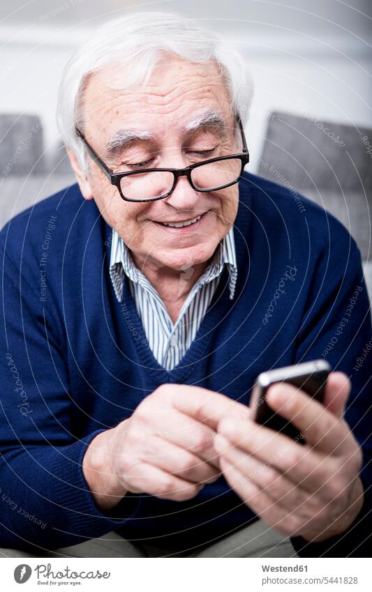 Senior man using smartphone mobile phone mobiles mobile phones Cellphone cell phone cell phones reading sitting Seated message text messaging SMS Text Message