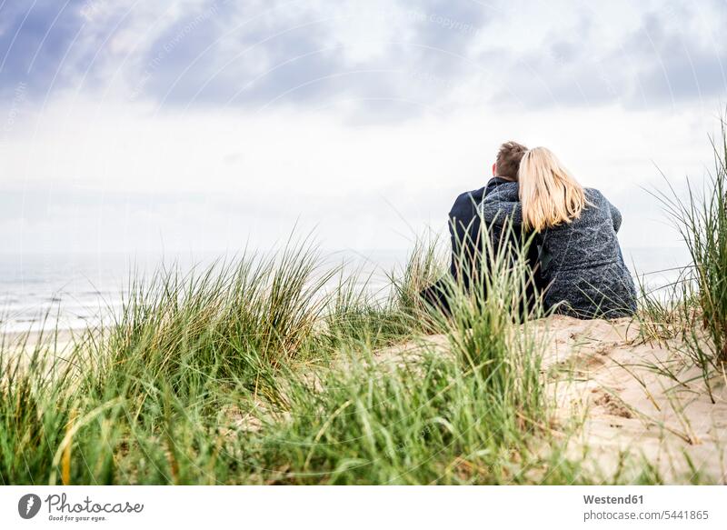 Couple sitting in dunes couple twosomes partnership couples beach beaches relaxed relaxation Seated sand dune sand dunes people persons human being humans