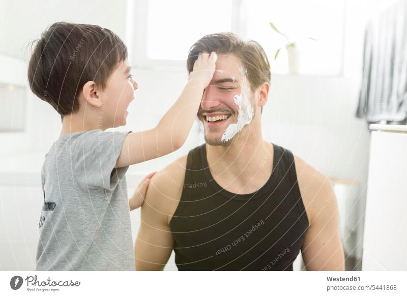 Playful son applying shaving foam on father's face sons manchild manchildren pa fathers daddy dads papa laughing Laughter Fun having fun funny family families
