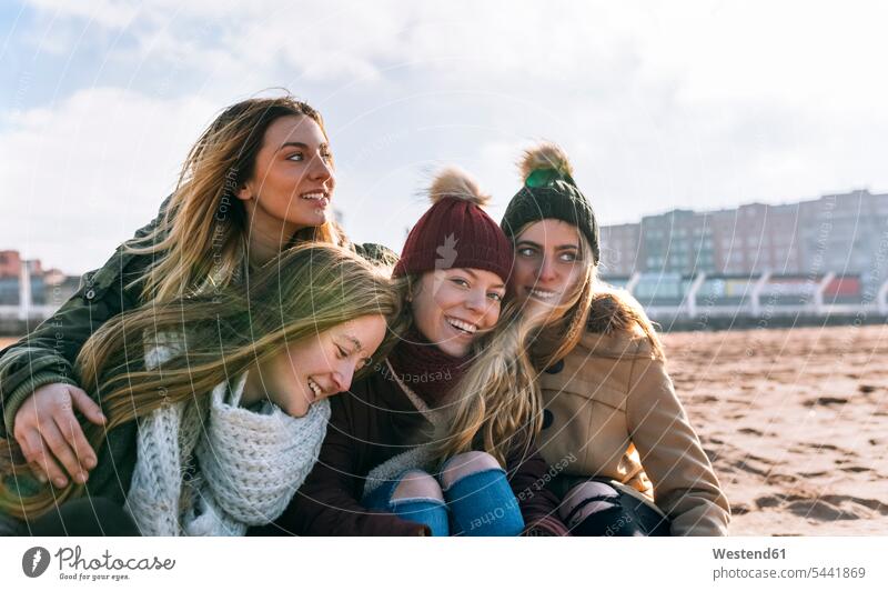 Four happy friends spending time together on the beach mate female friend beaches portraits smile seasons hibernal human human being human beings humans person