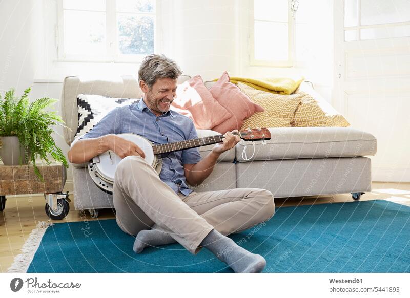 Man sitting on floor, playing the banjo relaxation relaxed relaxing banjos home at home Seated floors comfortable man men males musical instrument