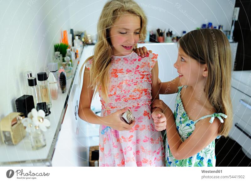 Two girls applying perfume in bathroom smiling smile females female friends flacons parfum parfumes perfumes child children kid kids people persons human being