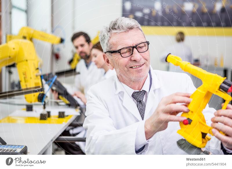 Engineer holding model of an industrial robot factory factories engineer engineers technology technologies engineering industry buckling arm robot business