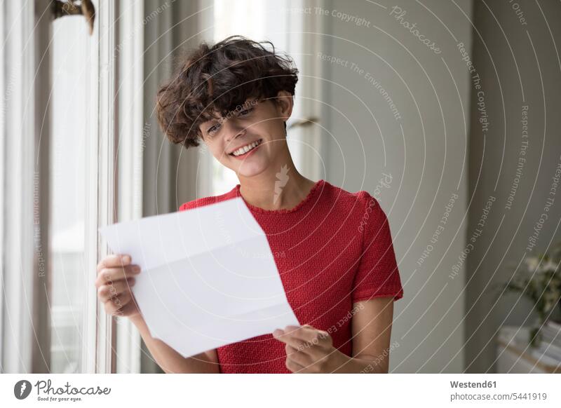 Portrait of smiling young woman reading a letter letter document letters females women mail post Adults grown-ups grownups adult people persons human being