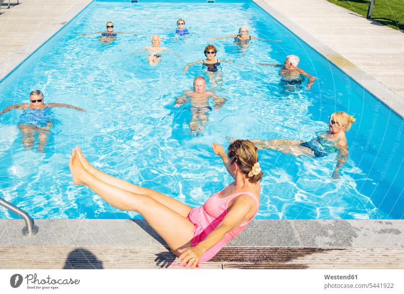 Group of seniors with trainer doing water gymnastics in pool senior adults old group of people groups of people swimming pool pools swimming pools aqua aerobics