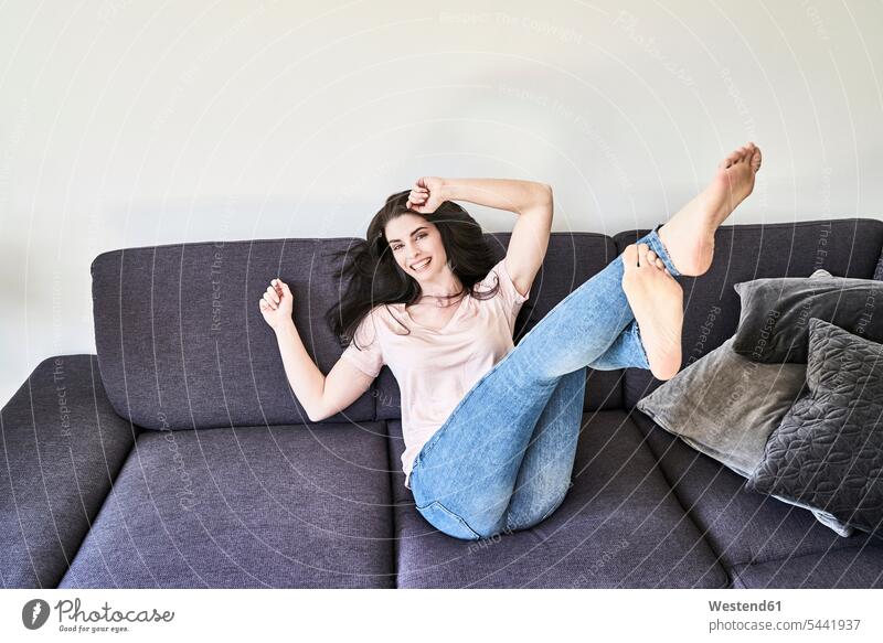 Playful young woman having fun on couch Fun funny relaxed relaxation females women laughing Laughter relaxing Adults grown-ups grownups adult people persons