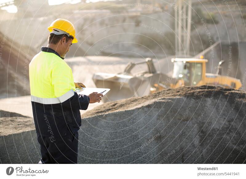Worker standing at quarry, using clipboard working At Work clipboards clip-board clip-boards clip board gravel pit worker blue collar worker workers
