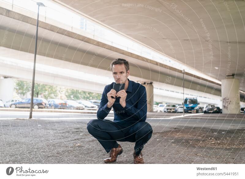 Businessman crouching at underpass holding tablet Business man Businessmen Business men digitizer Tablet Computer Tablet PC Tablet Computers iPad Digital Tablet