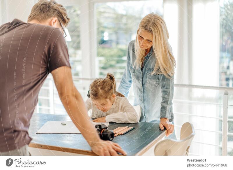 Mature woman and man looking at girl drawing at home relaxed relaxation females girls smiling smile watching women painting relaxing child children kid kids
