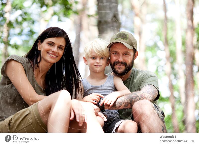 Portrait of happy family with son in forest sons manchild manchildren smiling smile families portrait portraits woods forests people persons human being humans