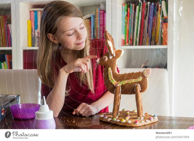 Smiling girl with homemade gingerbread reindeer at home Gingerbread Ginger bread females girls caribu caribou reindeers smiling smile child children kid kids