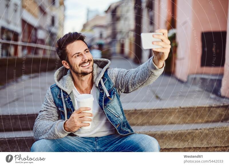 Man taking selfie holding coffee and sitting on stairs Selfie Selfies mobile phone mobiles mobile phones Cellphone cell phone cell phones smiling smile man men