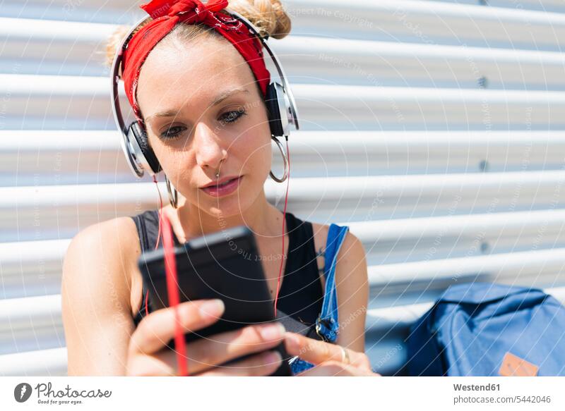 Portrait of young woman with headphones looking at smartphone females women Smartphone iPhone Smartphones headset Adults grown-ups grownups adult people persons