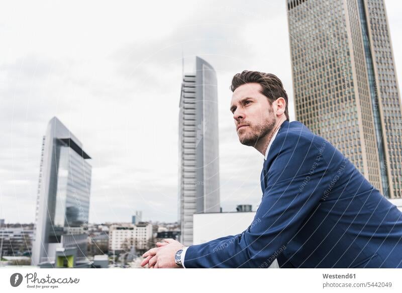 Businessman in front of skyskrapers, looking pensive thinking decision deciding decide decisions Success successful high-rise multistorey building