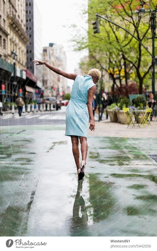 USA, New York, young blonde african-american woman walking in puddle African-American Ethnicity Afro-American African American Ethnicity African Americans