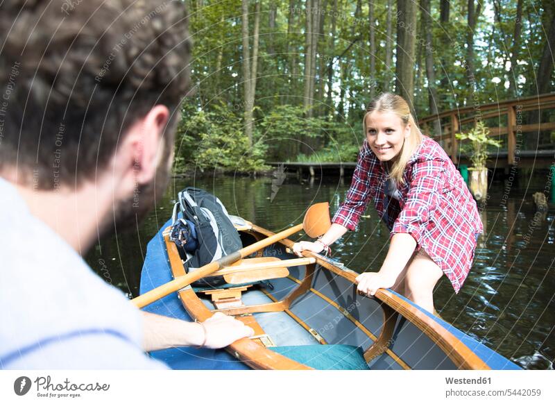 Happy young couple entering canoe in a forest brook getting in getting into board boarding brooks rivulet twosomes partnership couples happiness happy woods
