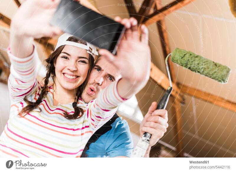 Young couple renovating their new home, taking smart phone selfies DIY Doityourself Do it yourself Do-it-yourself home ownership private owned home renovation