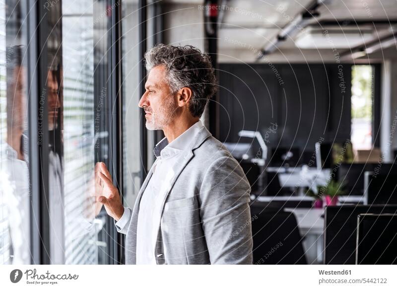 Mature businessman in office loooking out of window offices office room office rooms Businessman Business man Businessmen Business men looking view seeing
