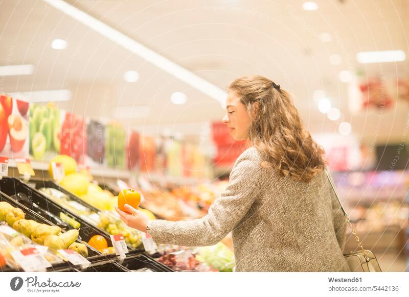 Young woman choosing kaki in supermarket supermarkets choose Kaki Kakis Persimmons females women Fruit Fruits Food foods food and drink Nutrition Alimentation