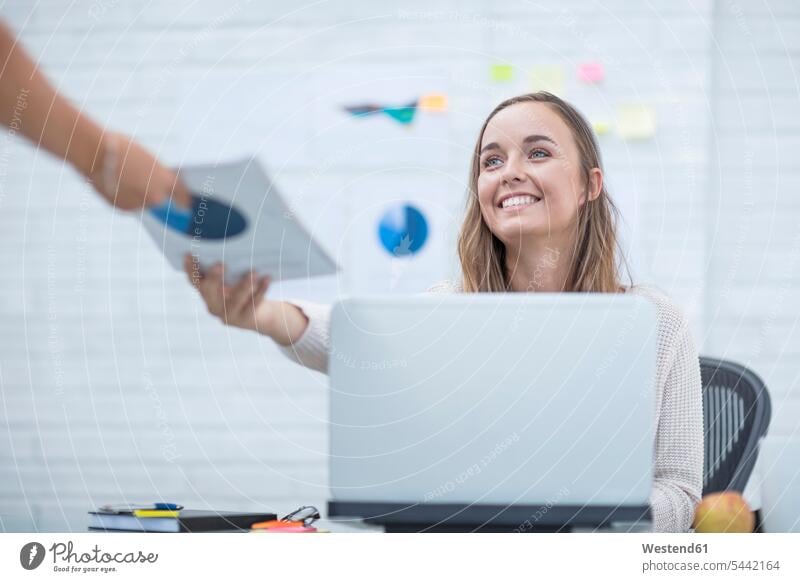 Young woman working in office taking documents office worker At Work happiness happy take sitting Seated desk desks Joy enjoyment pleasure Pleasant delight