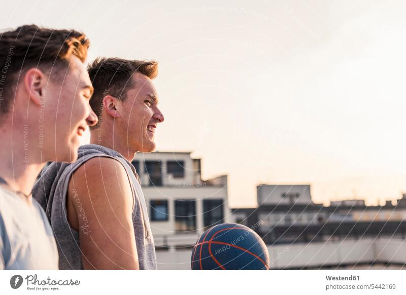Friends playing basketball at sunset on a rooftop young friends mate basketballs happiness happy Fun having fun funny fit friendship Basketball sport sports