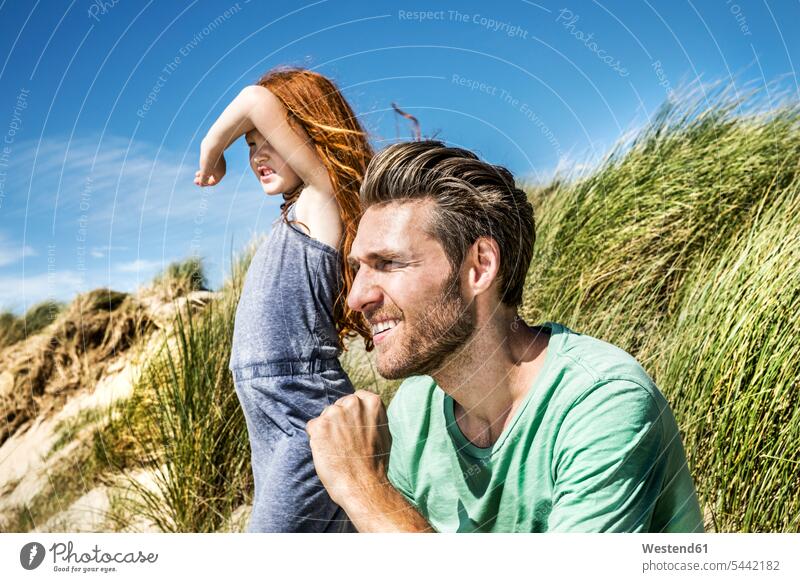 Netherlands, Zandvoort, father and daughter on in beach dunes looking out beaches family families pa fathers daddy dads papa daughters smiling smile people