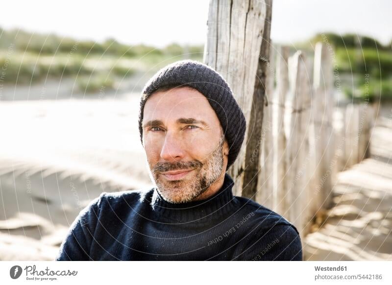 Portrait of smiling man at fence on the beach relaxed relaxation smile beaches men males portrait portraits relaxing Adults grown-ups grownups adult people