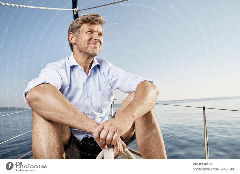 Portrait of smiling mature man sittiing on his sailing boat looking at distance men males Adults grown-ups grownups adult people persons human being humans