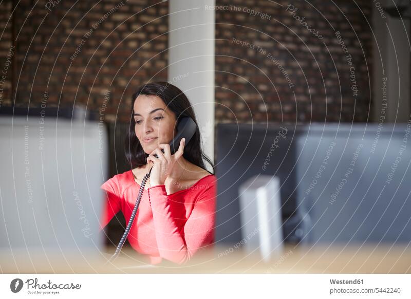 Businesswoman sitting in office, making a call businesswoman businesswomen business woman business women working At Work Seated smiling smile entrepreneur