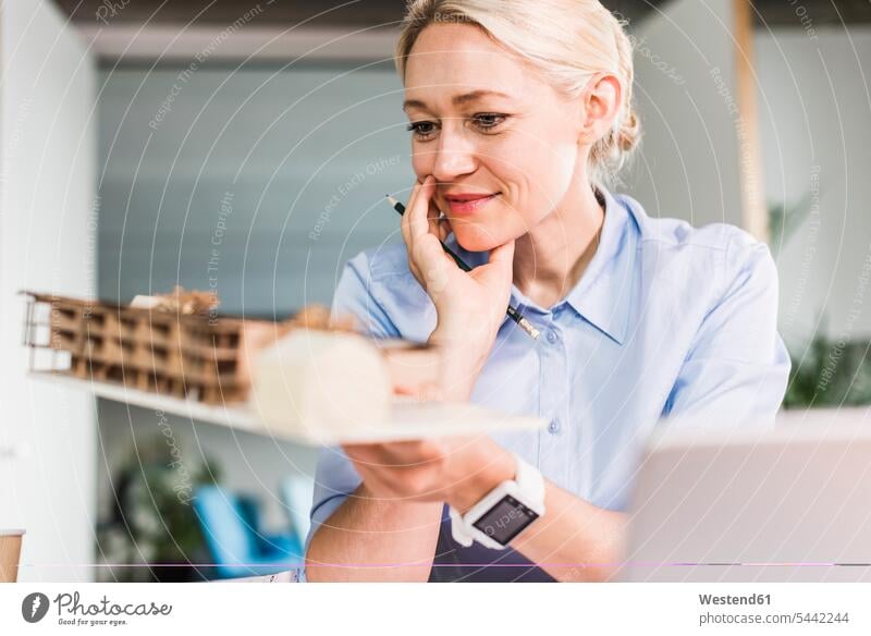 Woman in office holding architectural model smiling smile businesswoman businesswomen business woman business women working At Work looking eyeing
