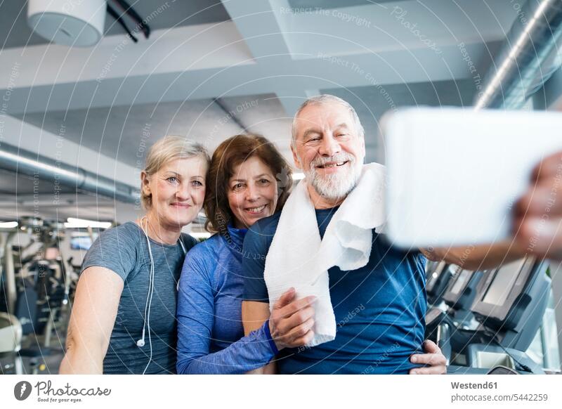 Group of fit seniors in gym taking a selfie with smartphone after working out senior adults old mobile phone mobiles mobile phones Cellphone cell phone