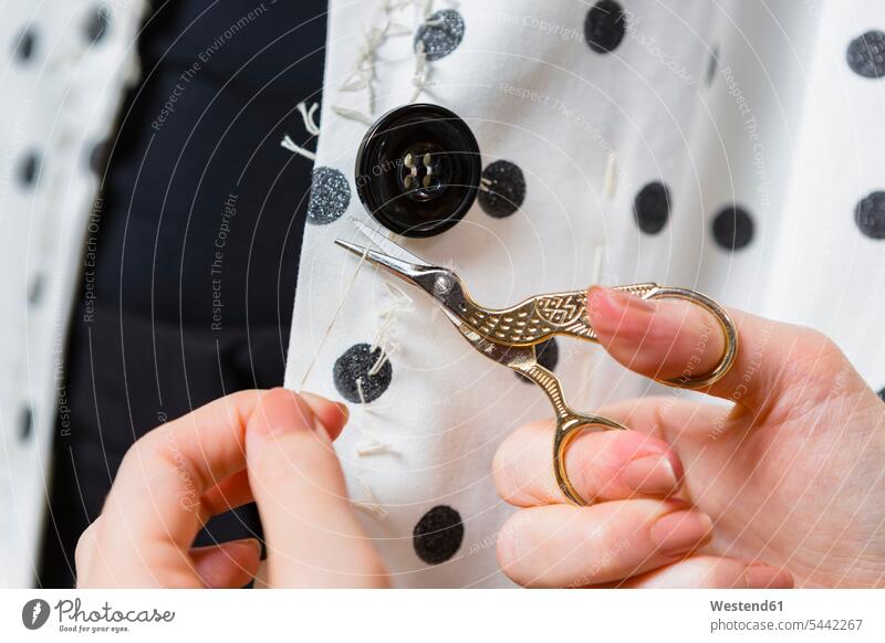Woman's hands stitching button on a dress, close-up buttons human hand human hands people persons human being humans human beings scissors Scissor thread