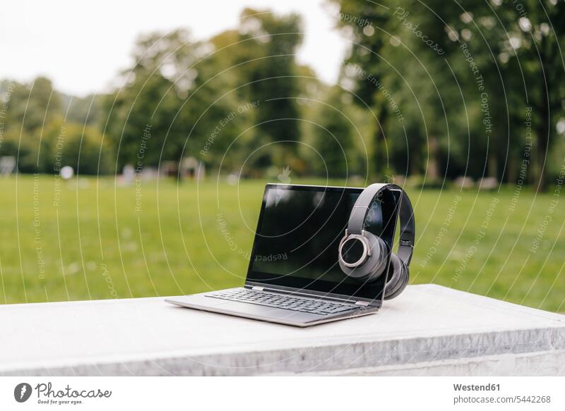 Laptop and headphones on a wall in a park headset parks walls laptop Laptop Computers laptops notebook computer computers outdoors outdoor shots location shot