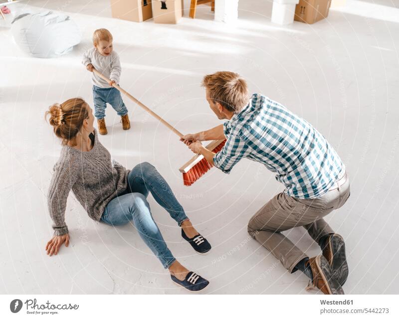Father and daughter having fun with a broom in a loft brooms family families daughters lofts Fun funny father pa fathers daddy dads papa people persons