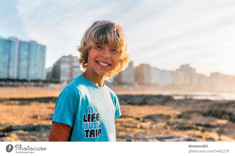 Portrait of smiling blond on the beach at sunset boy boys males portrait portraits child children kid kids people persons human being humans human beings smile